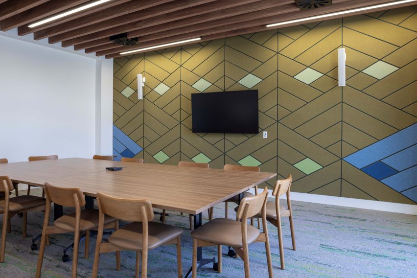 Meeting room with a wooden table and 11 chairs in the centre, with a TV on the far wall.