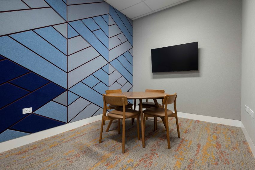 Small room with a wooden table and 4 chairs in the centre, with a TV on the far wall.