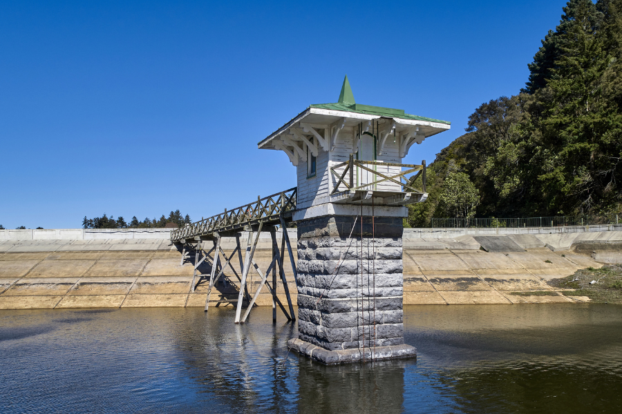 Small structure sticking out from concrete wall sitting on calm water